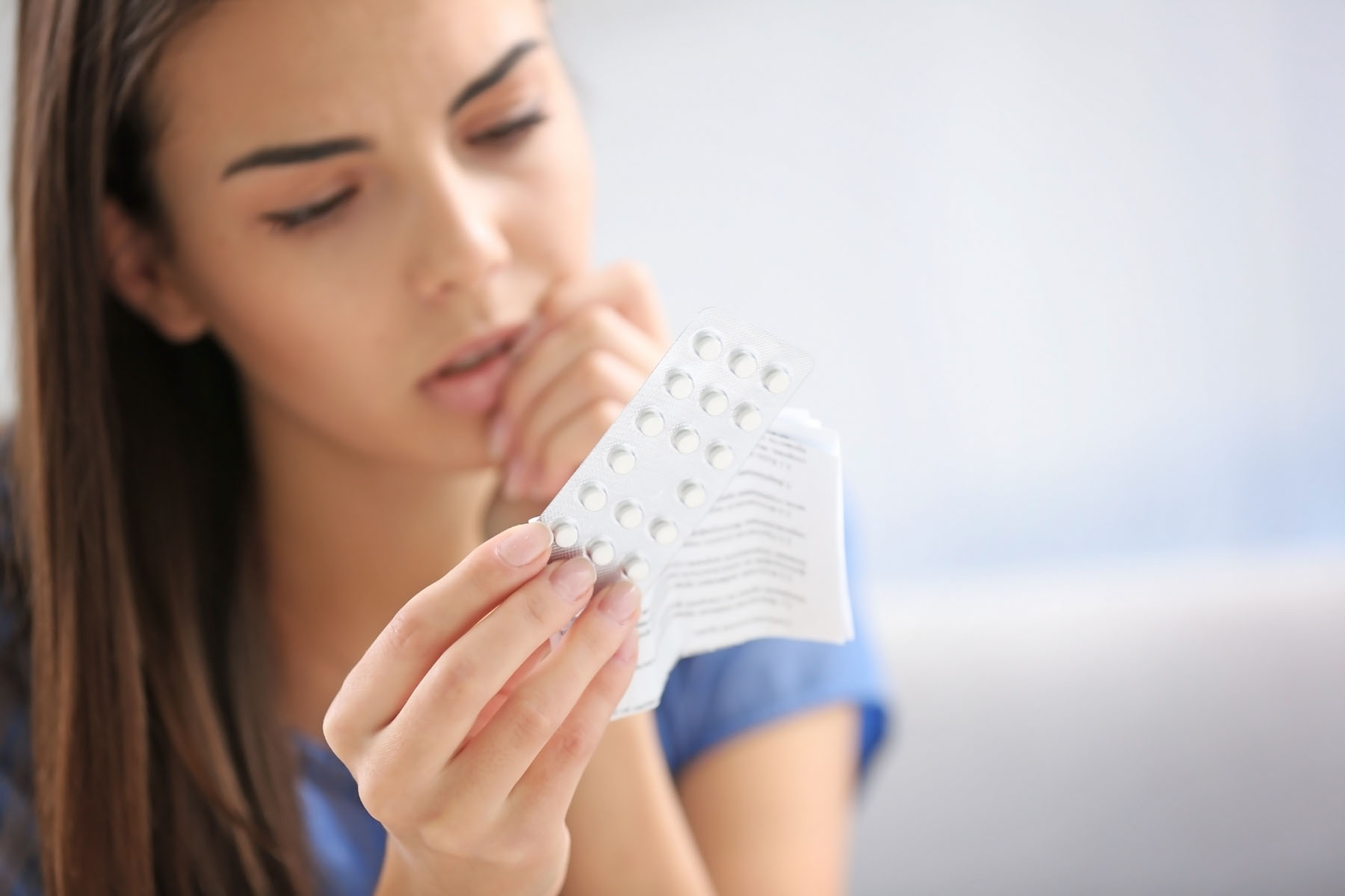 Eine Frau hält einen Pillenblister in der Hand und liest die Verpackungsbeilage.